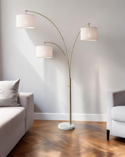 74" Brass Three Light Arc Floor Lamp With Off White Fabric Drum Shade
